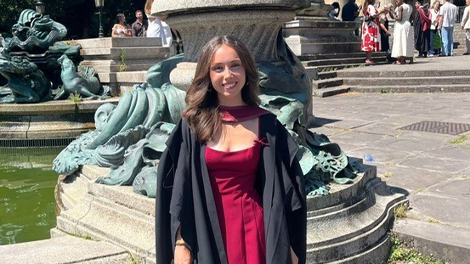 a person in a red dress standing in front of a fountain
