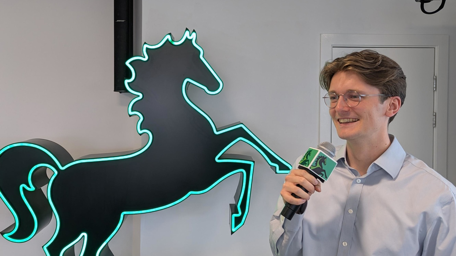 a person holding a microphone and standing in front of a horse statue
